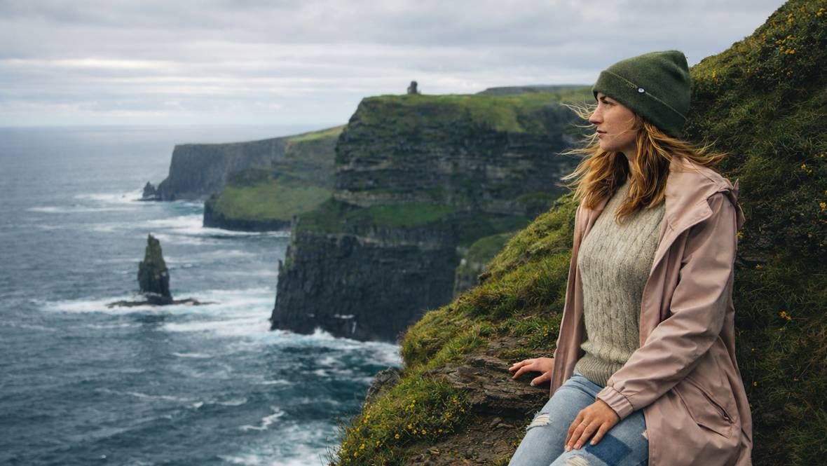 AI illustration of a woman sitting on an Irish cliff overlooking the Atlantic Ocean