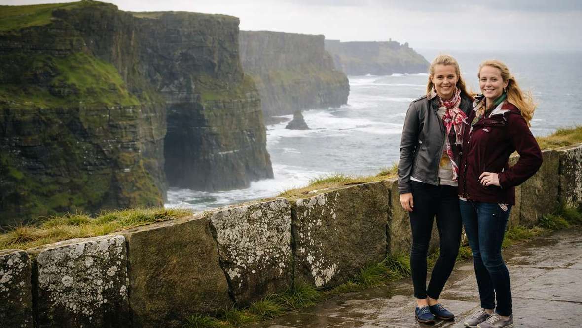 AI illustration of two women standing before ocean cliffs in Ireland